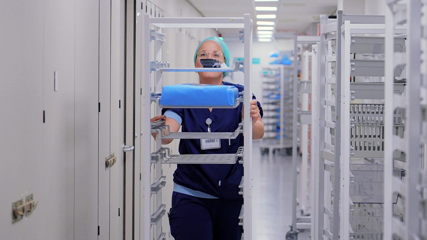 Medewerkster van een centrale sterilisatieafdeling met een kar vol instrumentensets